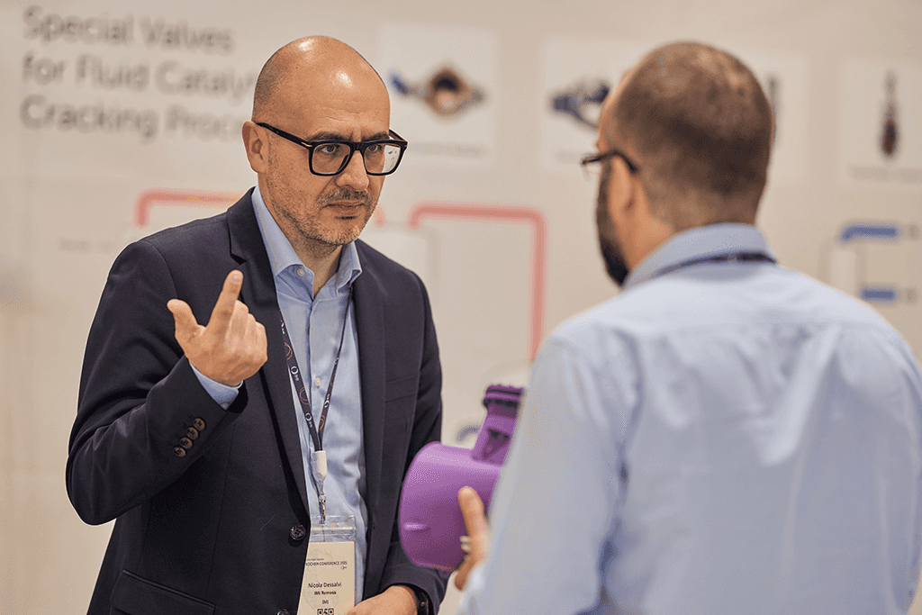Nicola Dessalvi discusses a valve component with an attendee at the 2025 conference