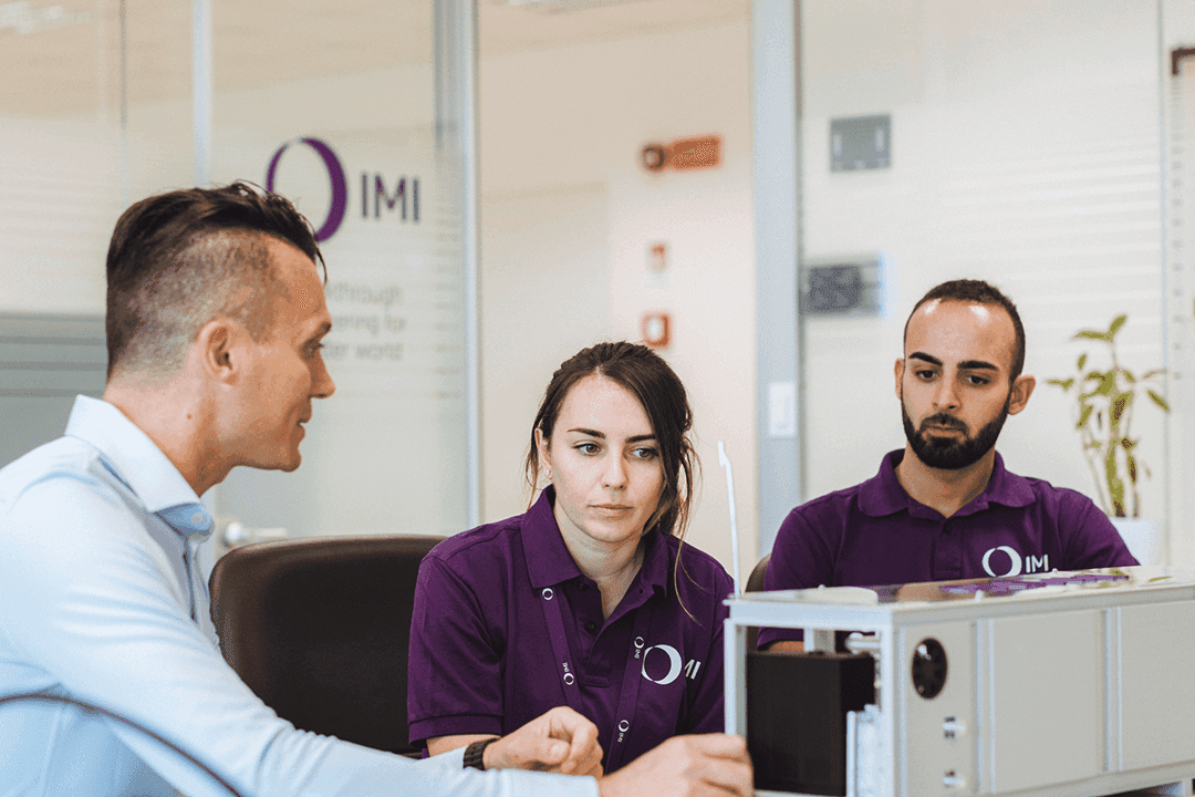 IMI Remosa team members demonstrating electrolyser model in office setting.