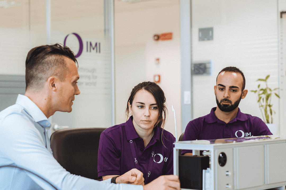 IMI Remosa team members demonstrating electrolyser model in office setting.