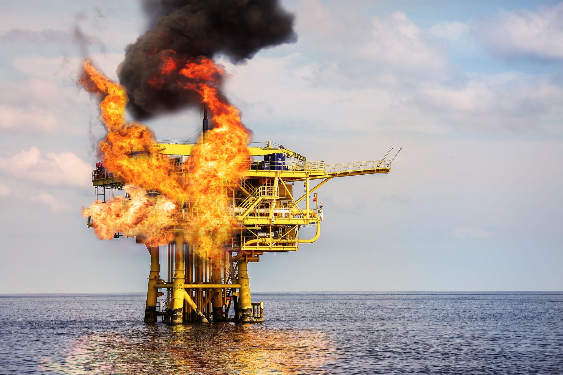 oil rig in ocean with visible flames eminating from deck.