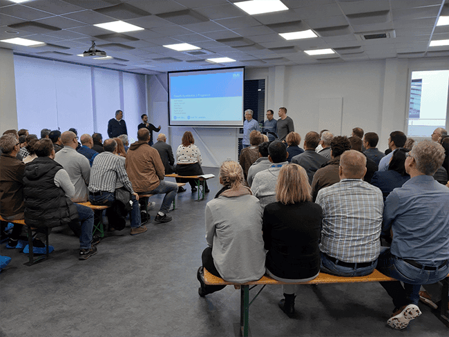 Employees seated in rows watching a presentation in a modern meeting room.