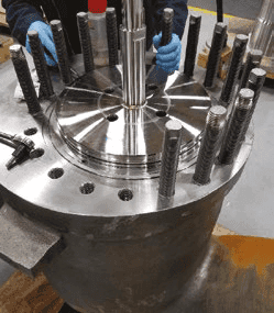 Assembly process showing piston rings being fitted onto a central plug with threaded rods.