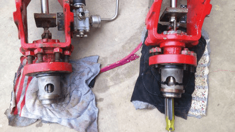 Two red mechanical valves showing surface wear, with one valve visibly more eroded than the other.